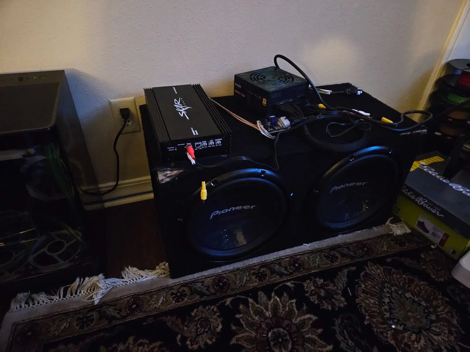 Two Pioneer 12-inch subwoofers with a SKAR car amplifier and EVGA ATX power supply resting on the enclosure